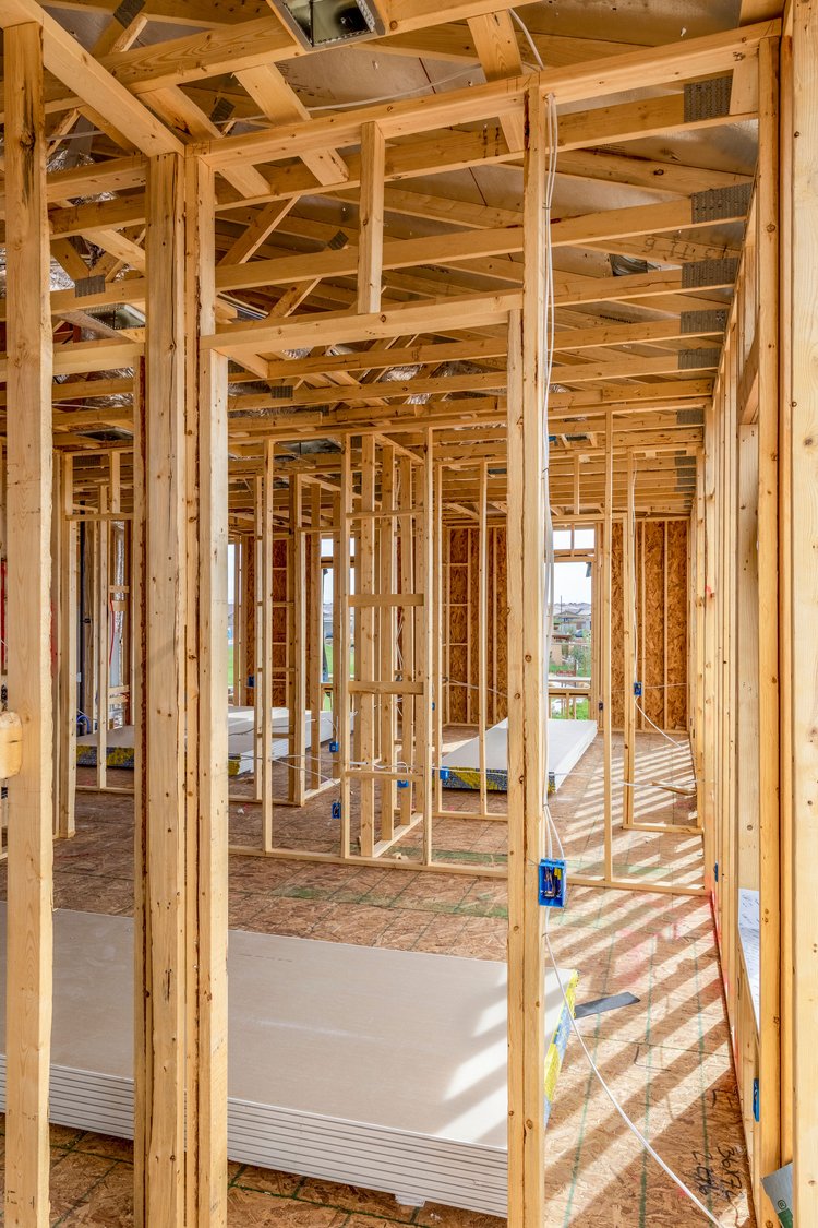 shutterstock_1915717933 Interior framework of a house under construction with exposed wooden studs and beams.