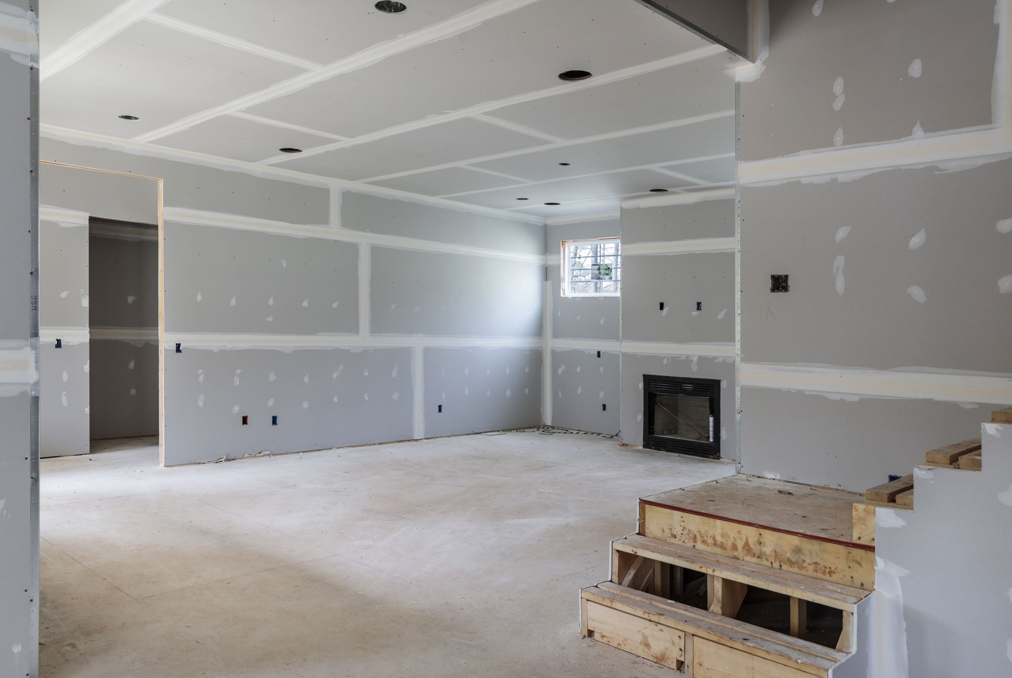 shutterstock_656375515 Interior of a room under construction with unfinished drywall and a fireplace insert.